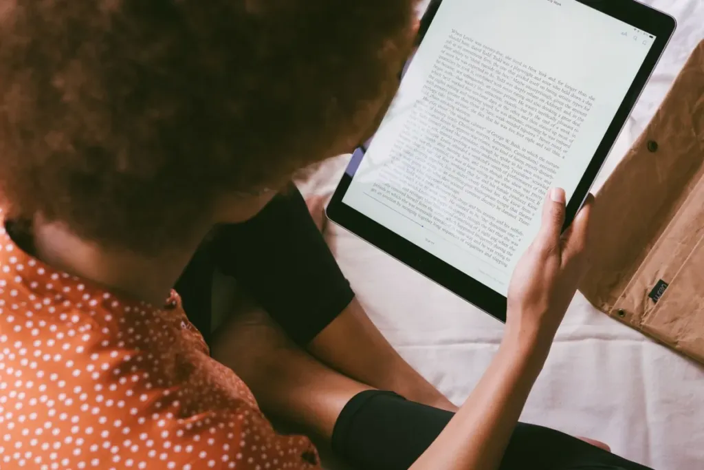 Person reading a long article on a tablet while sitting on a bed