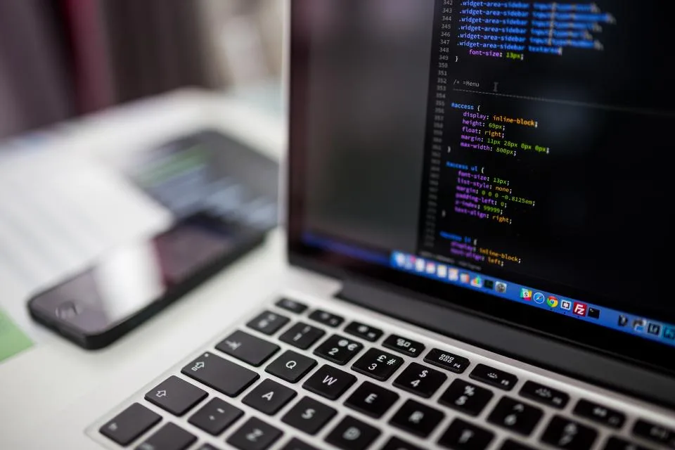 Code editor open on a MacBook screen with a phone on the desk